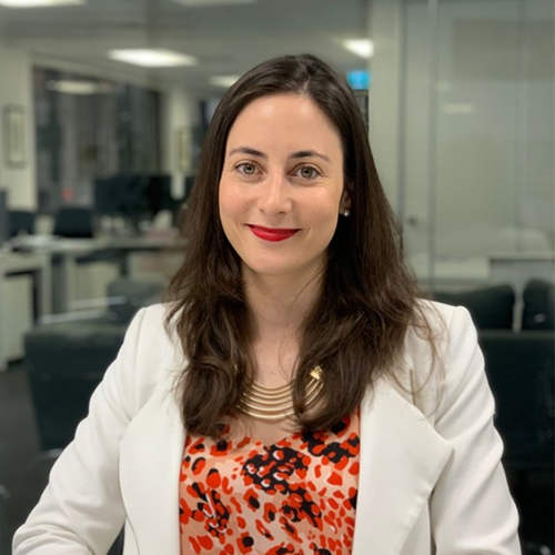 A woman with long dark hair, red lipstick and white blazer.